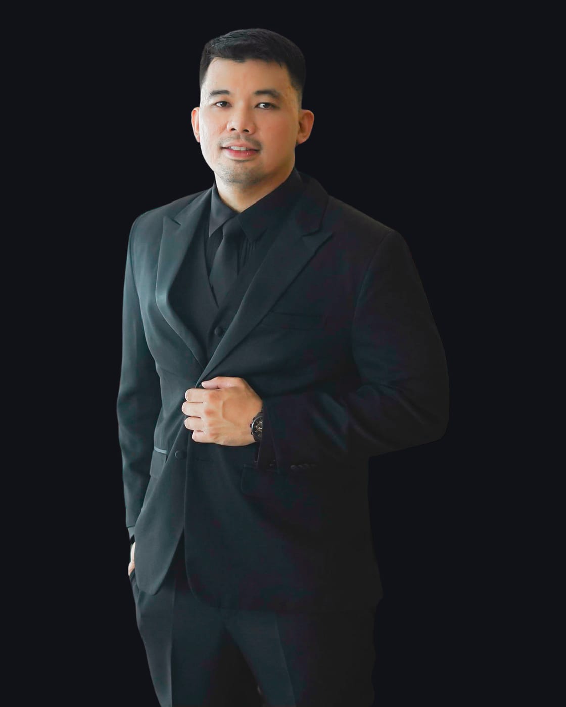John Lozada, in a black suit, cut out against a dark ground